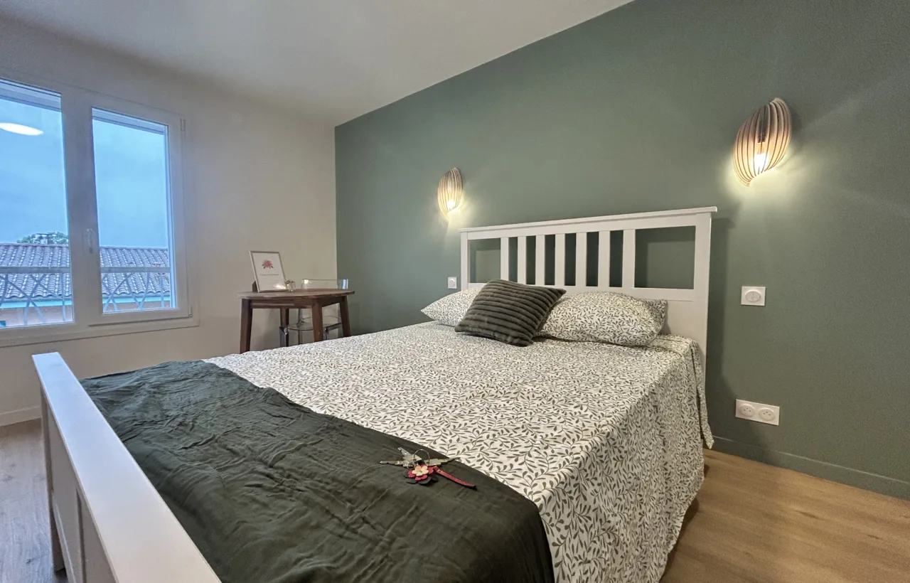 Chambre lumineuse avec mur vert et vue dégagée sur le jardin