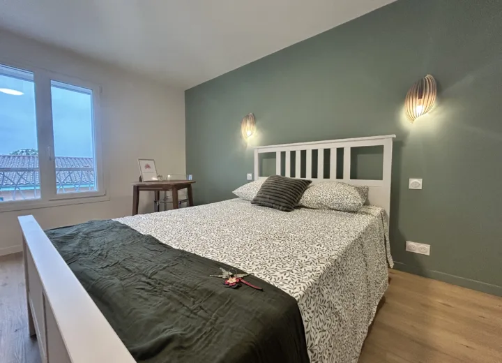 Chambre lumineuse avec mur vert et vue dégagée sur le jardin
